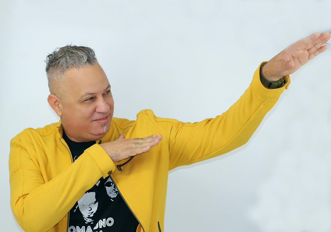 El vocalista de ALJADAQUI con chaqueta amarilla posando sobre fondo blanco