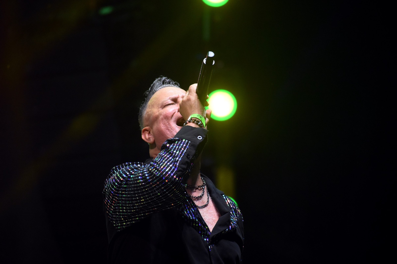 El vocalista de Aljadaqui cantando en vivo bajo luces verdes del escenario